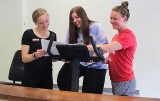 Three women focusing on accountability in front of a counter.