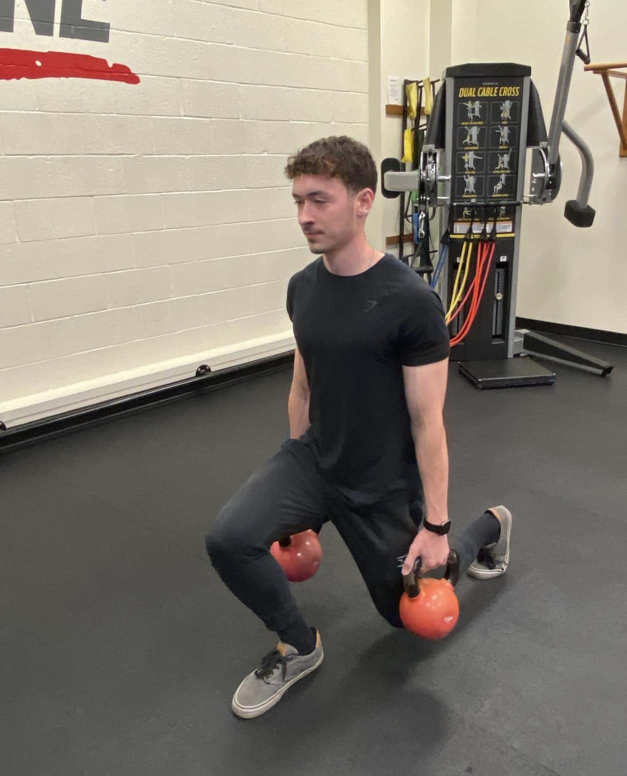 Colton Dash completing a lunge with kettlebells