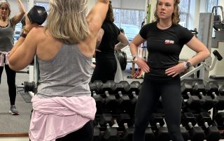 Dumbbell exercises during one-on-one personal fitness training session at a gym.
