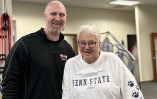 Motivated elderly woman receiving personalized one-on-one fitness training at a professional gym.