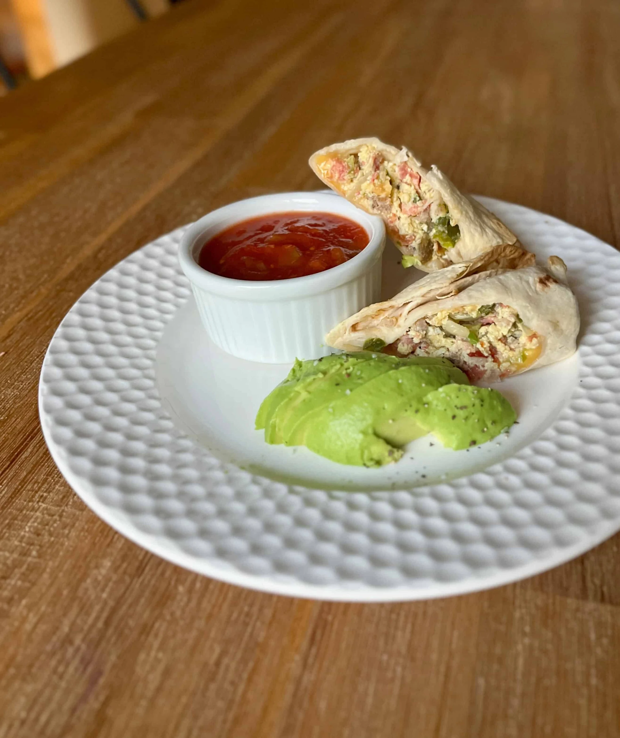 Breakfast burrito served with avocado and salsa