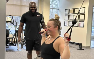 Trainer putting client through lat pulldown exercise