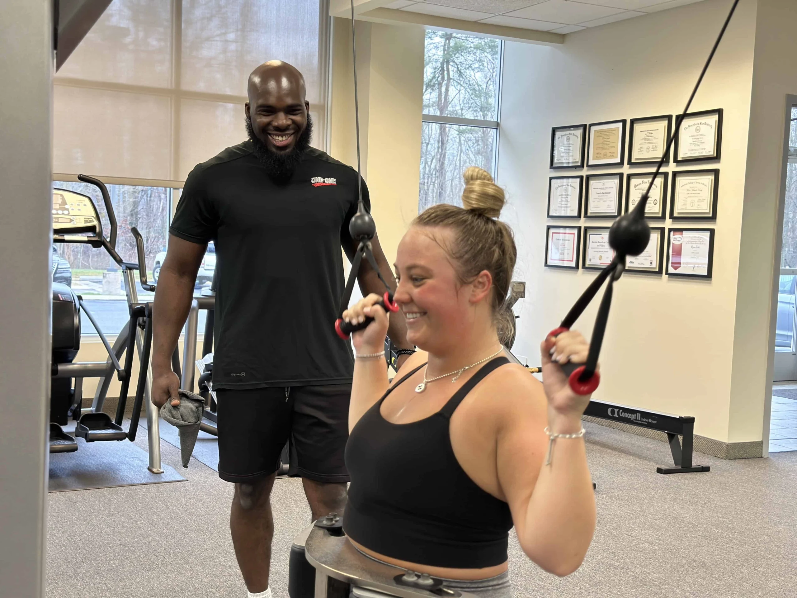 Trainer putting client through lat pulldown exercise